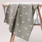 Forest deer muslin swaddle draped over a wooden changing table